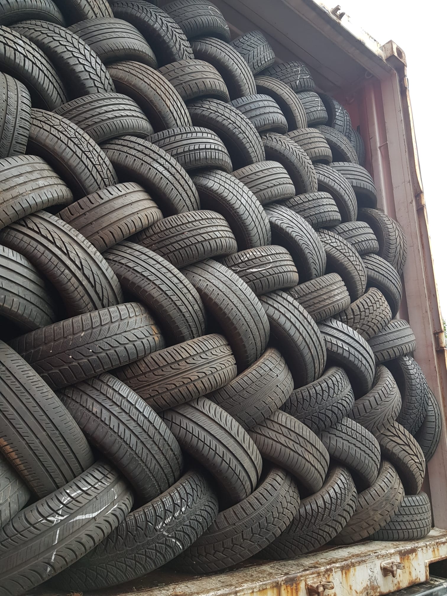 Wall-to-wall tripled passenger tyres filling a container